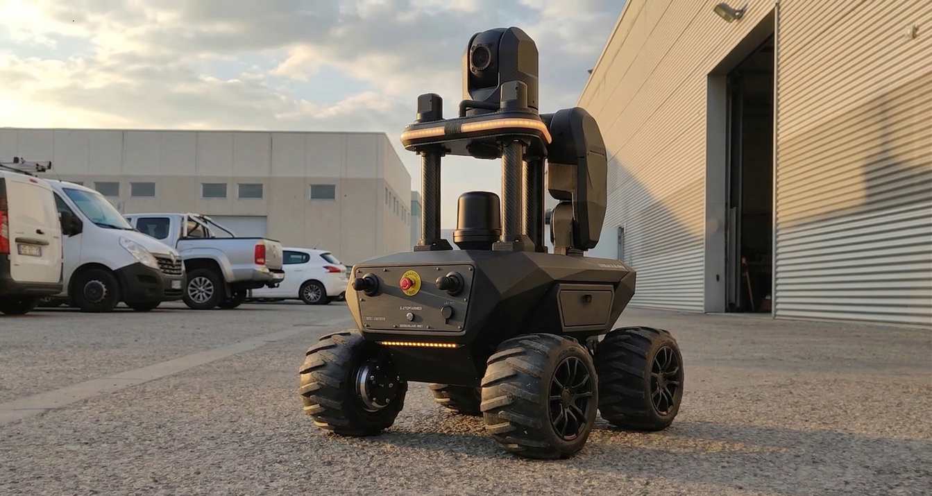 Autonomous security robot patrolling a high-value asset corridor with LiDAR sensor pod and auto-charge docking station visible in background